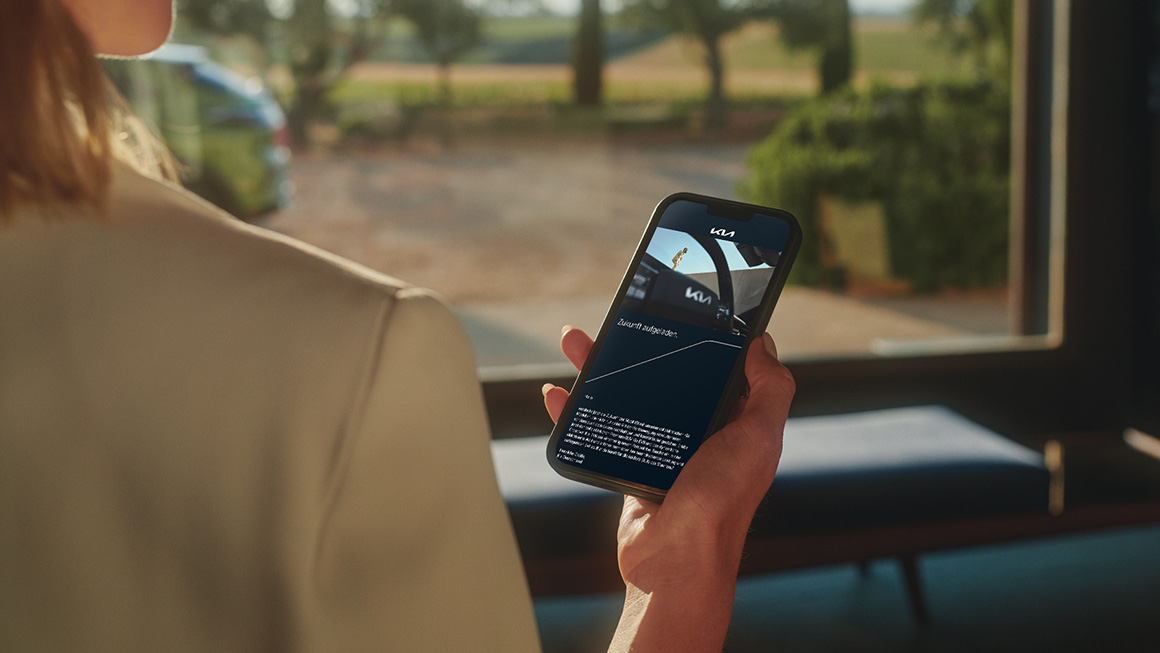 Frau schaut auf Mobiltelefon mit EV-Newsletter