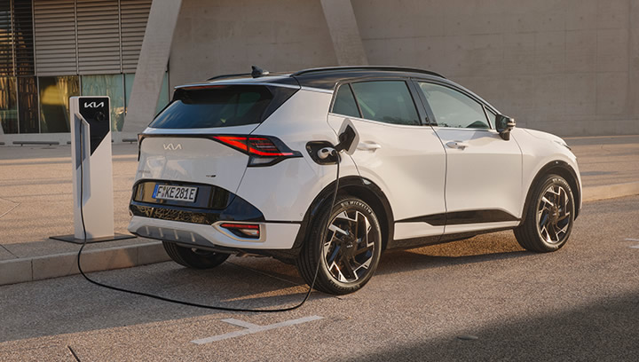Kia EV9 GT, Nahaufnahme Scheinwerfer Fahrerseite, Frau lehnt an Fahrzeug