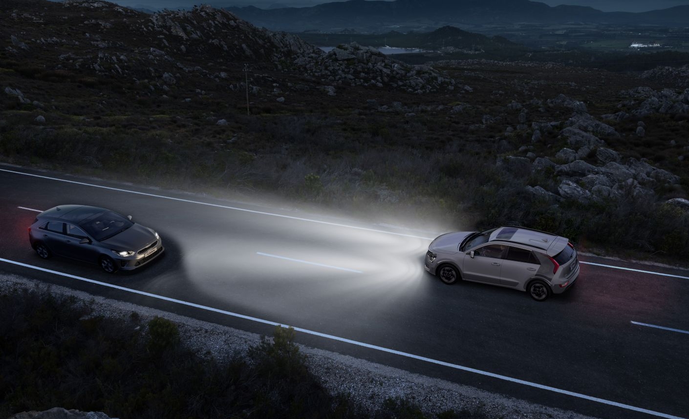 Coche Kia circulando de noche con luces encendidas