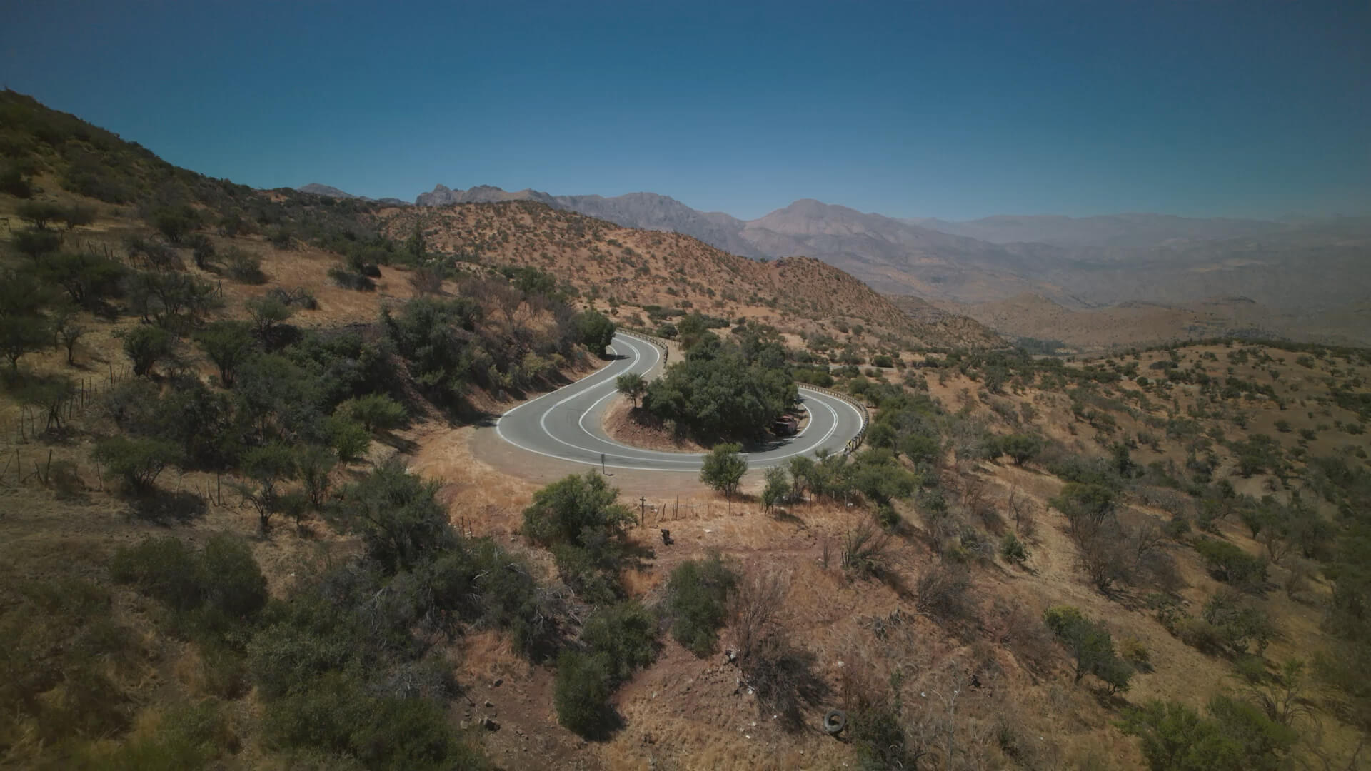 Kia Soundscapes Video-Loop: Ein Kia EV9 in Pebble Grey Metallic fährt auf einer staubigen Straße durch eine Wüstenlandschaft. 
