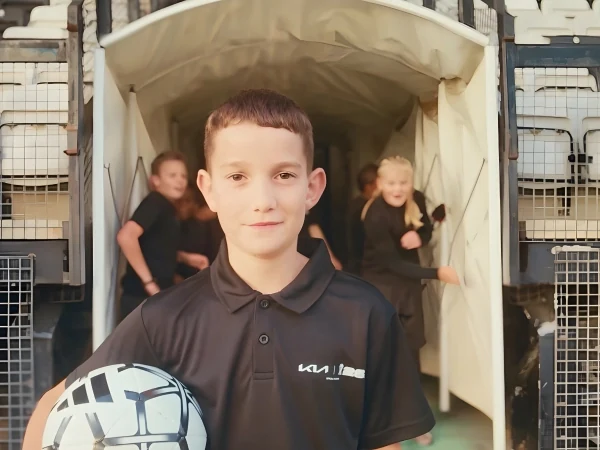 Imagen de un jugador juvenil sosteniendo el balón oficial del partido antes de entrar al estadio.
