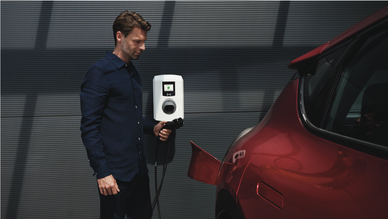 Ein Mann der einen Kia PBV an einer Ladesäule lädt.