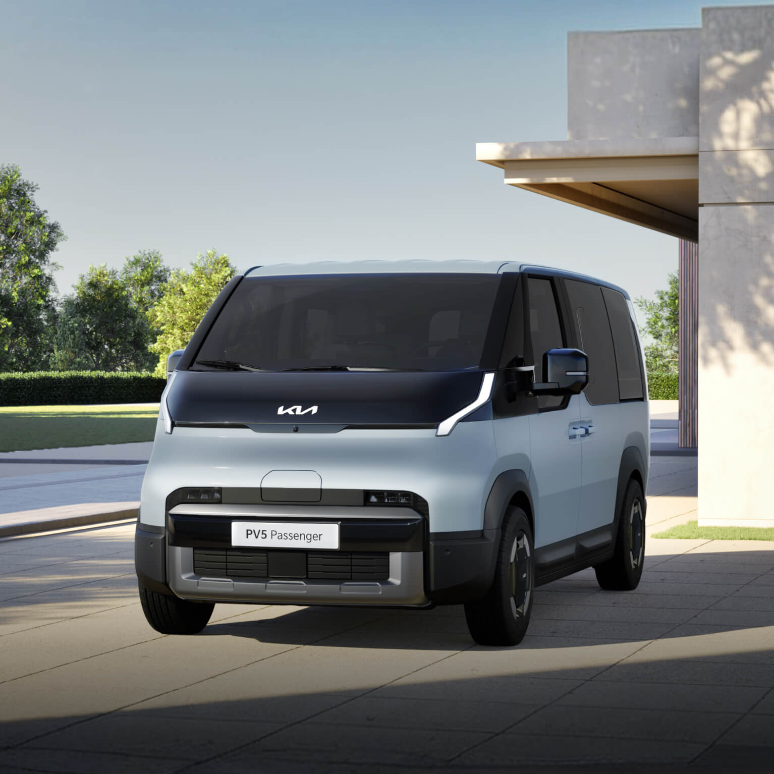 Vista frontale di Kia PV5 Passenger parcheggiato in un moderno contesto residenziale, mettendo in evidenza il design esterno pulito e geometrico