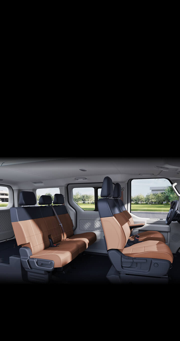 Vista anteriore degli interni di Kia PV5 Passenger che mette in risalto la grande visibilità offerta dal parabrezza, il comfort del volante riscaldato e la resistenza dei materiali dei sedili, ideali per l’uso quotidiano