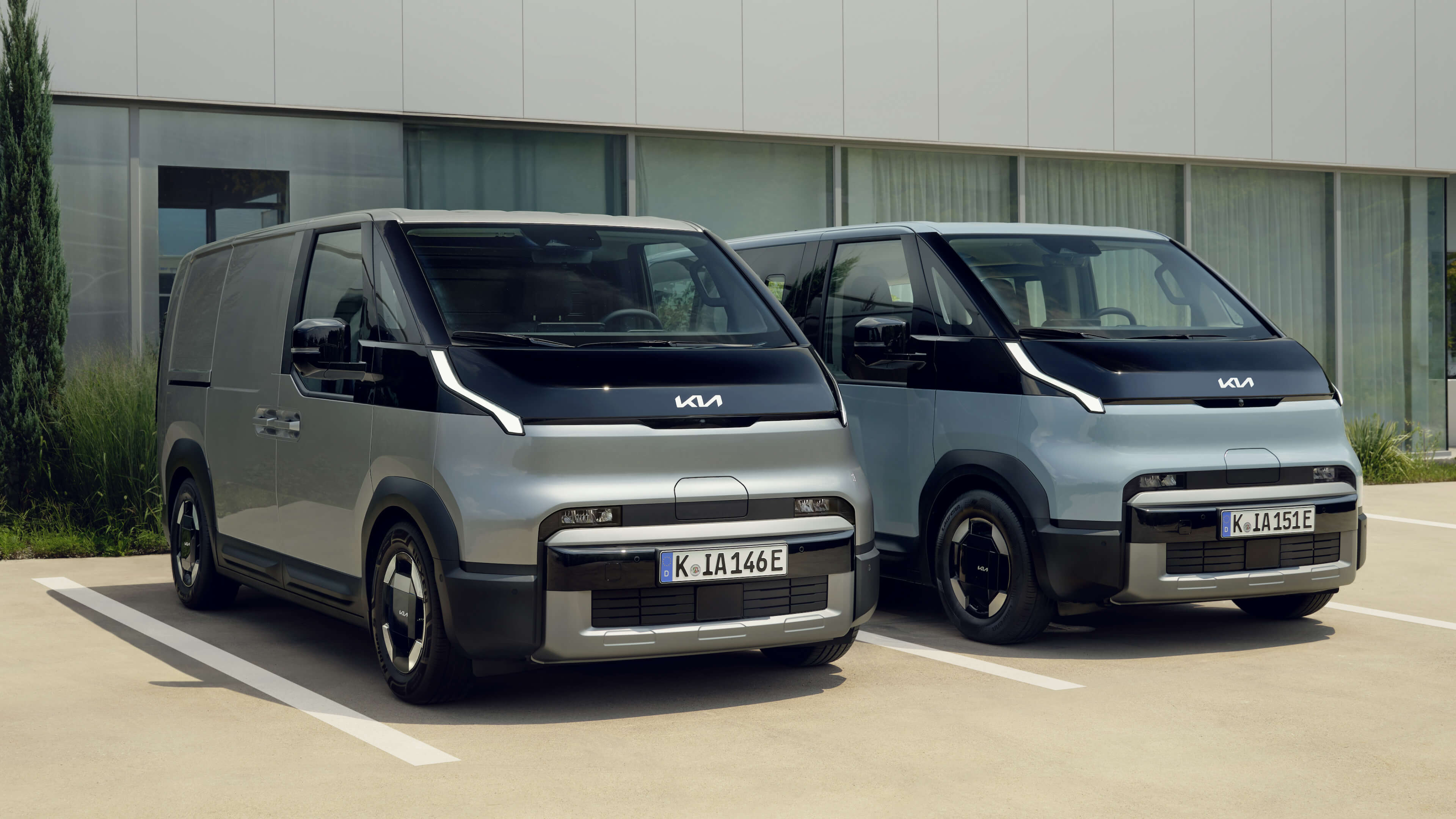 Frontansicht von zwei nebeneinanderstehenden Kia PV5.