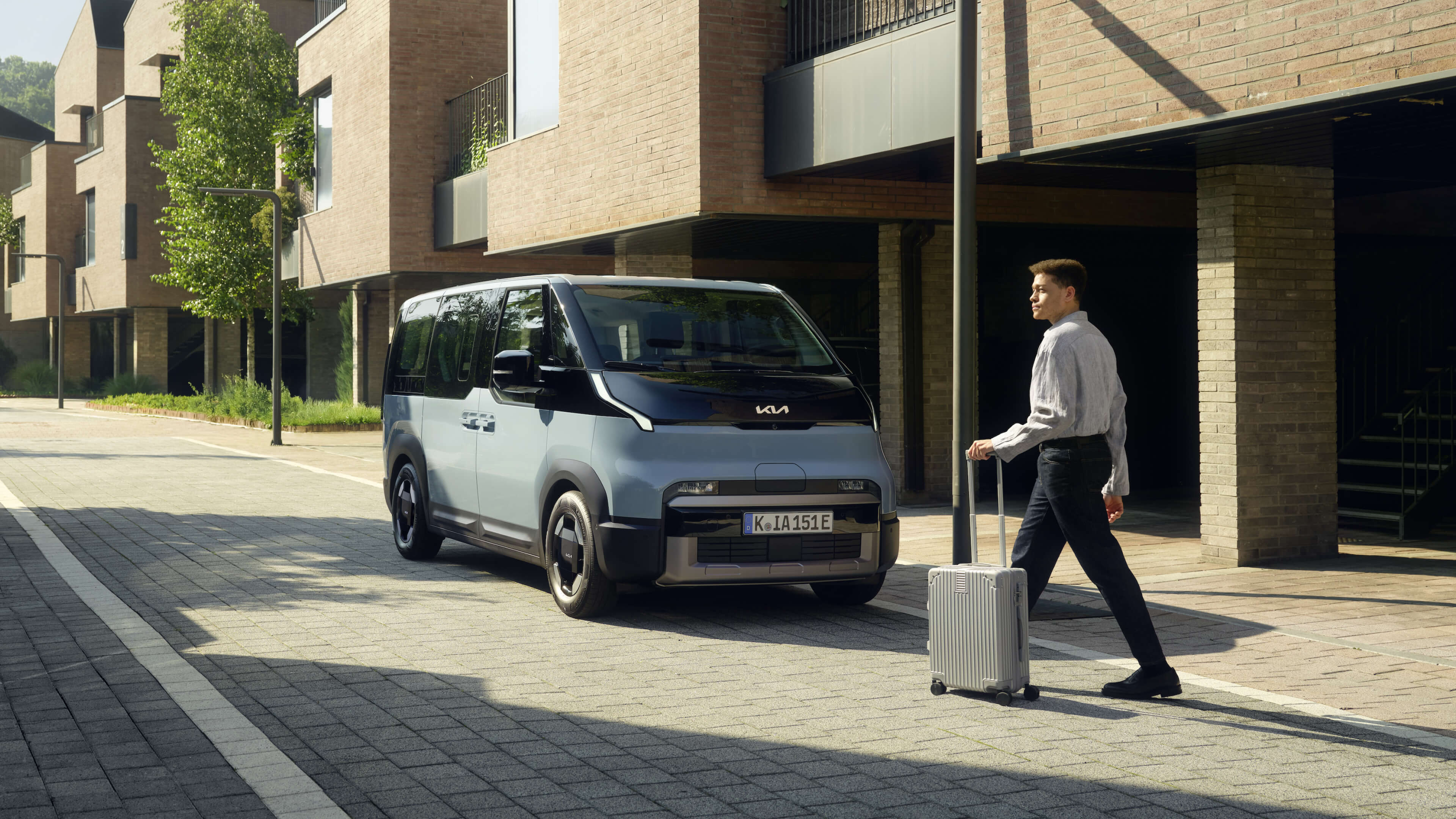 Mann mit Koffer läuft auf einen Kia PV5 zu.