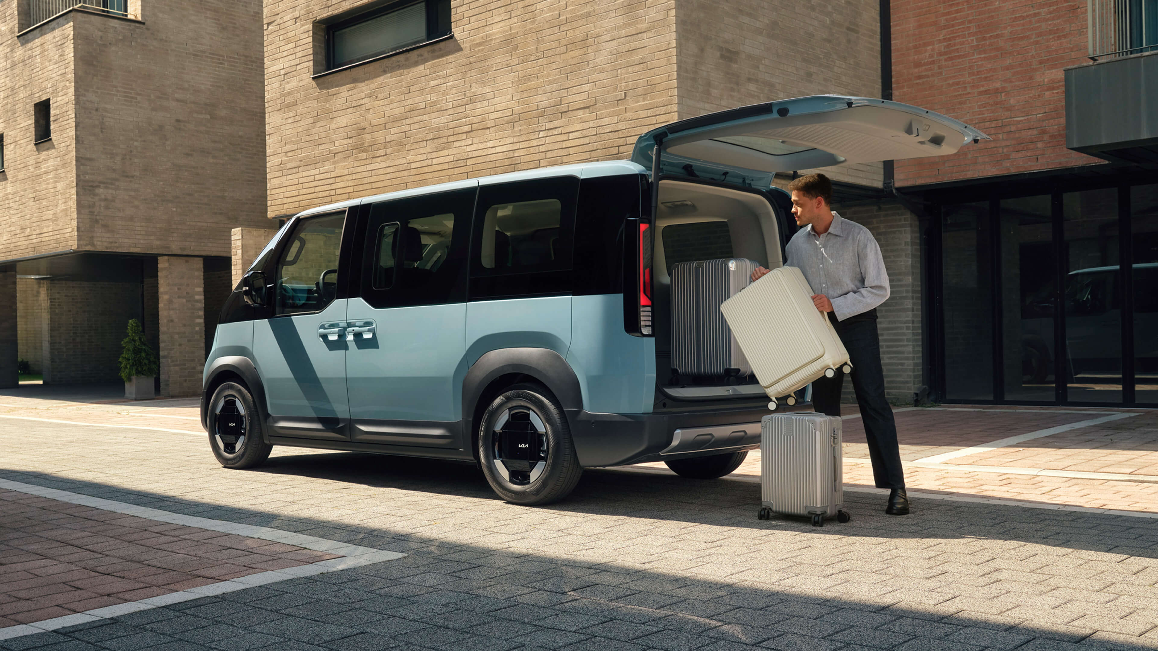 Ein Mann lädt mehrere Koffer in einen Kia PV5 Passenger.