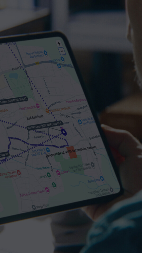 Ein Flottenmanager überprüft optimierte Lieferstrecken auf einer Tablet-Kartenansicht mit Fahrzeugrouten und Zielorten.
