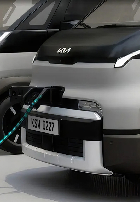 Partial front view of the Kia PV5 Cargo connected to charging station