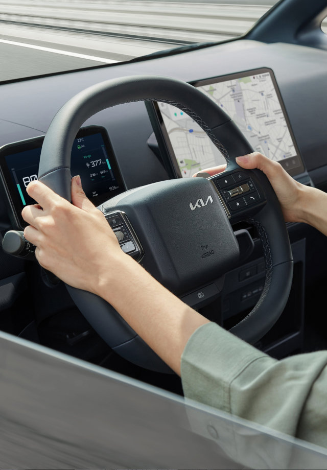 Close-up of a driver holding the Kia PV5 steering wheel
