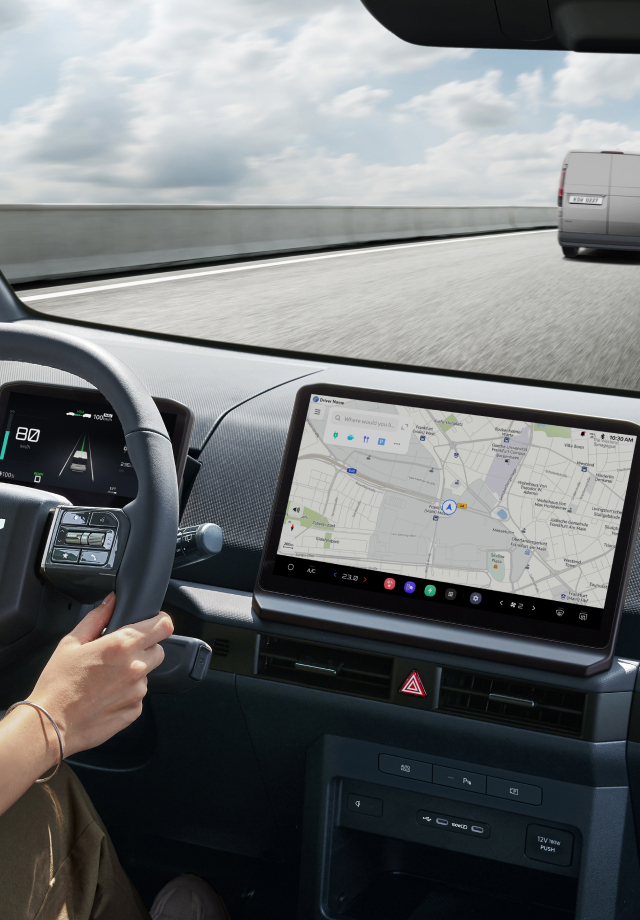 Interior view from the driver's seat with hands on the wheel and the navigation screen visible