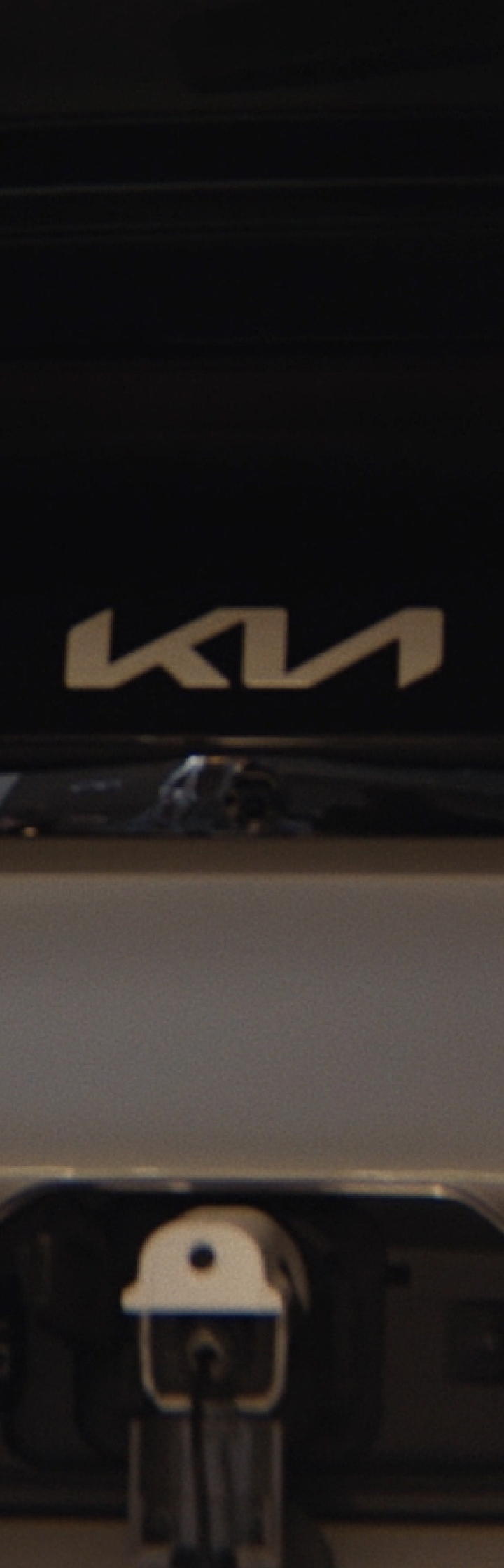 Rear view of the Kia PV5 Cargo charging with a man working on a laptop nearby