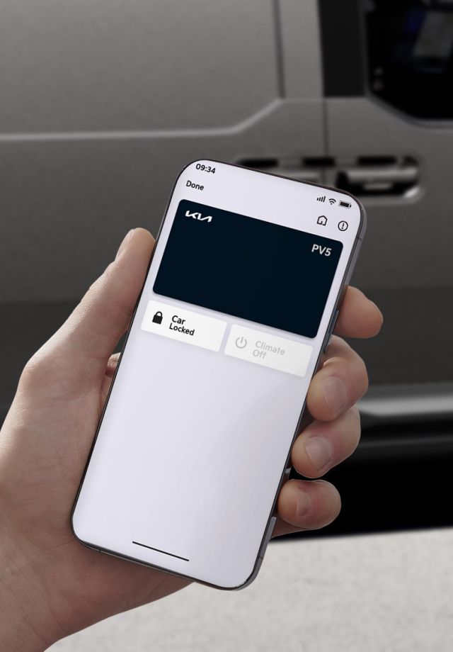 Hand holding smartphone displaying Kia PV5 digital key in front of van