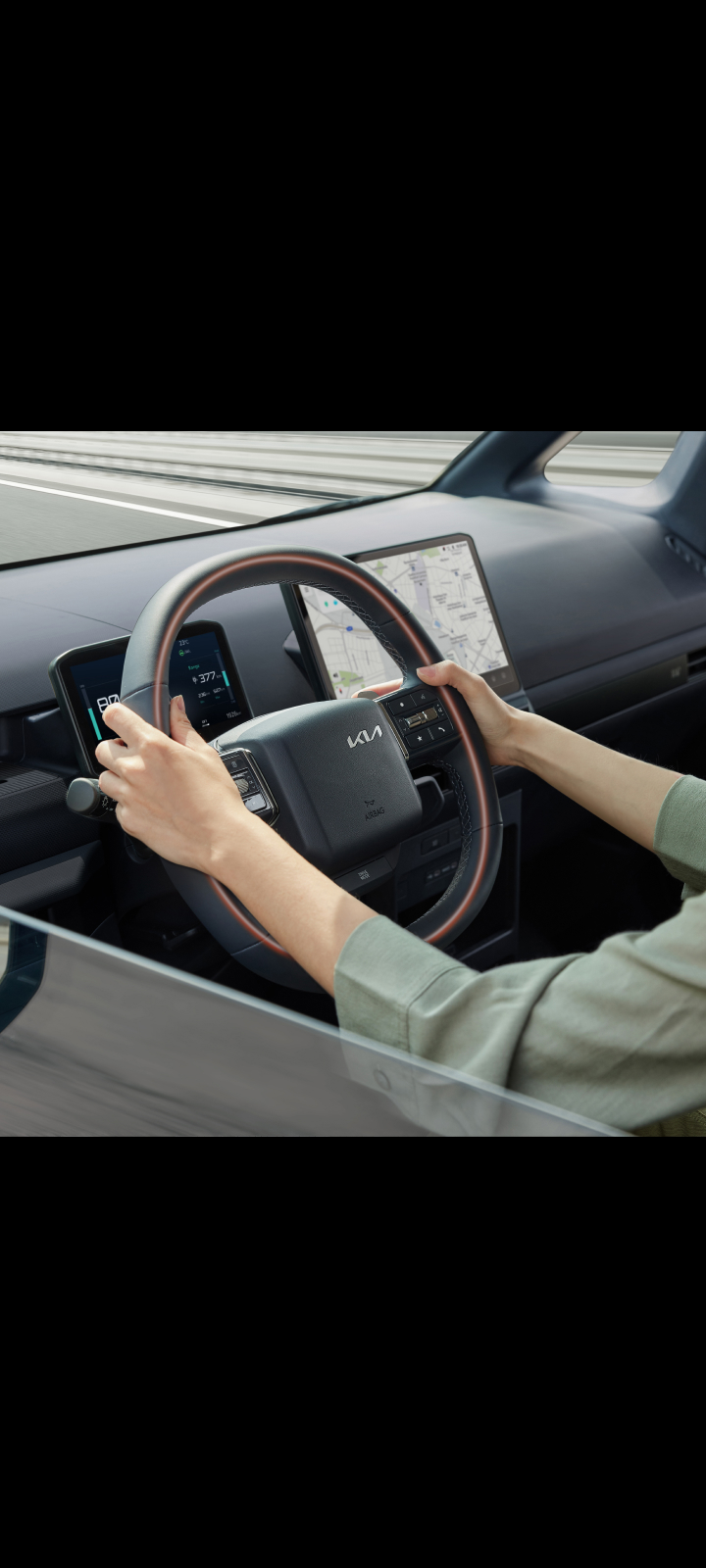 Close-up of the Kia PV5 Cargo steering wheel with driver’s hands
