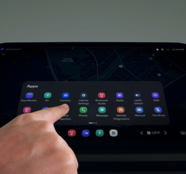 A finger touching a infotainment system touchscreen, which displays an apps menu in a vehicle