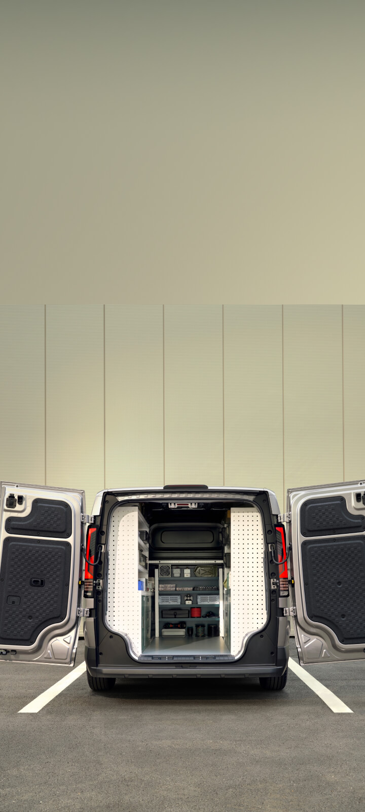 Female worker carrying toolbox beside the Kia PV5 Cargo with rear storage open