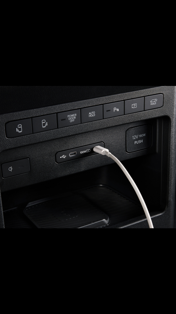 Close-up of the Kia PV5 Passenger dashboard USB port with cable connected