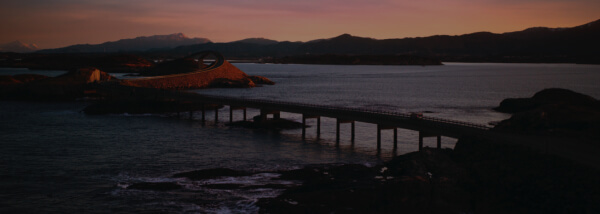 Blurred coastal landscape with a bridge at sunset
