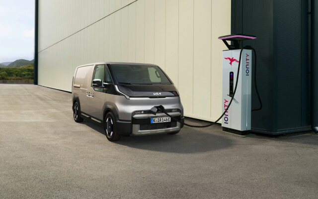 Front view of the Kia PV5 Passenger connected to charging station with visible powertrain overlay