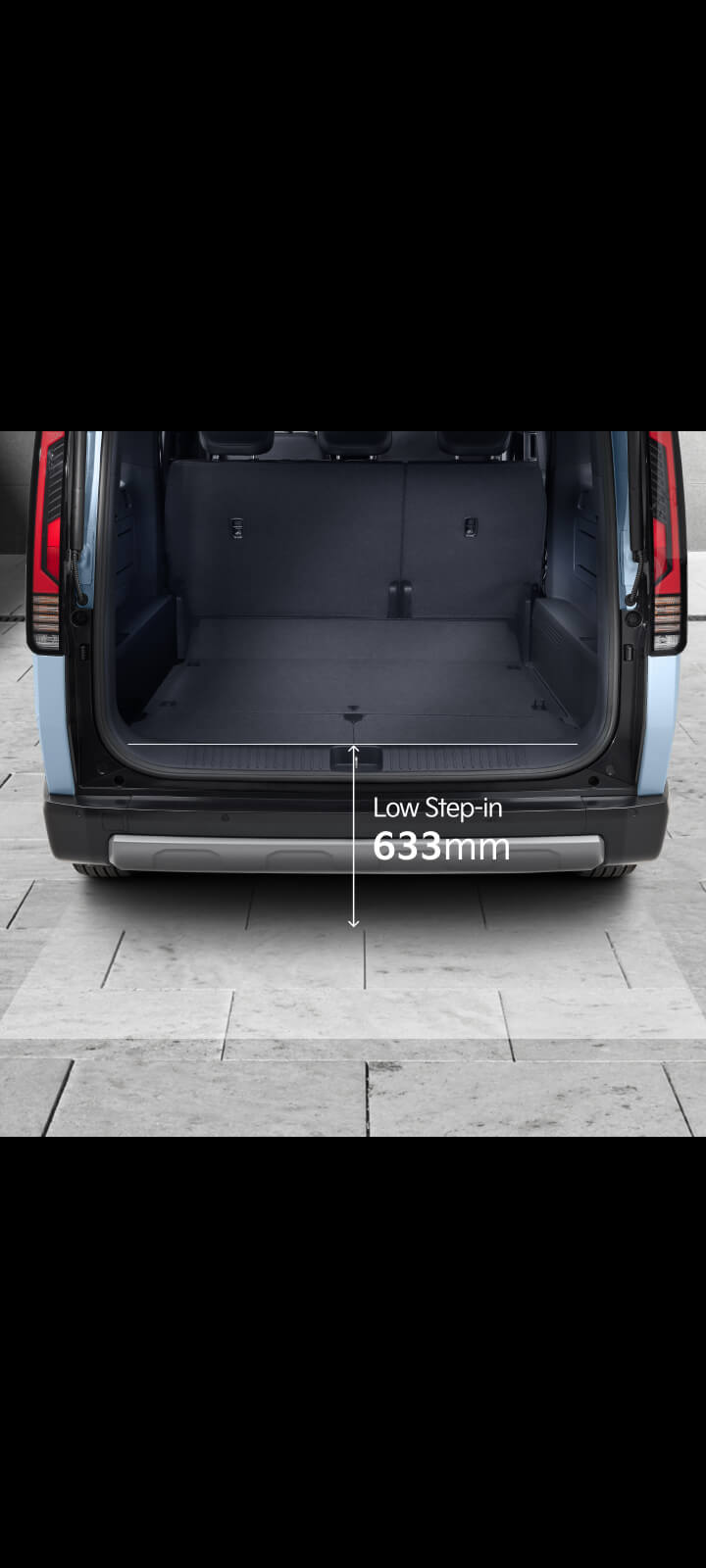 Rear cabin view of the Kia PV5 Passenger with foldable tray table and cup holder in use