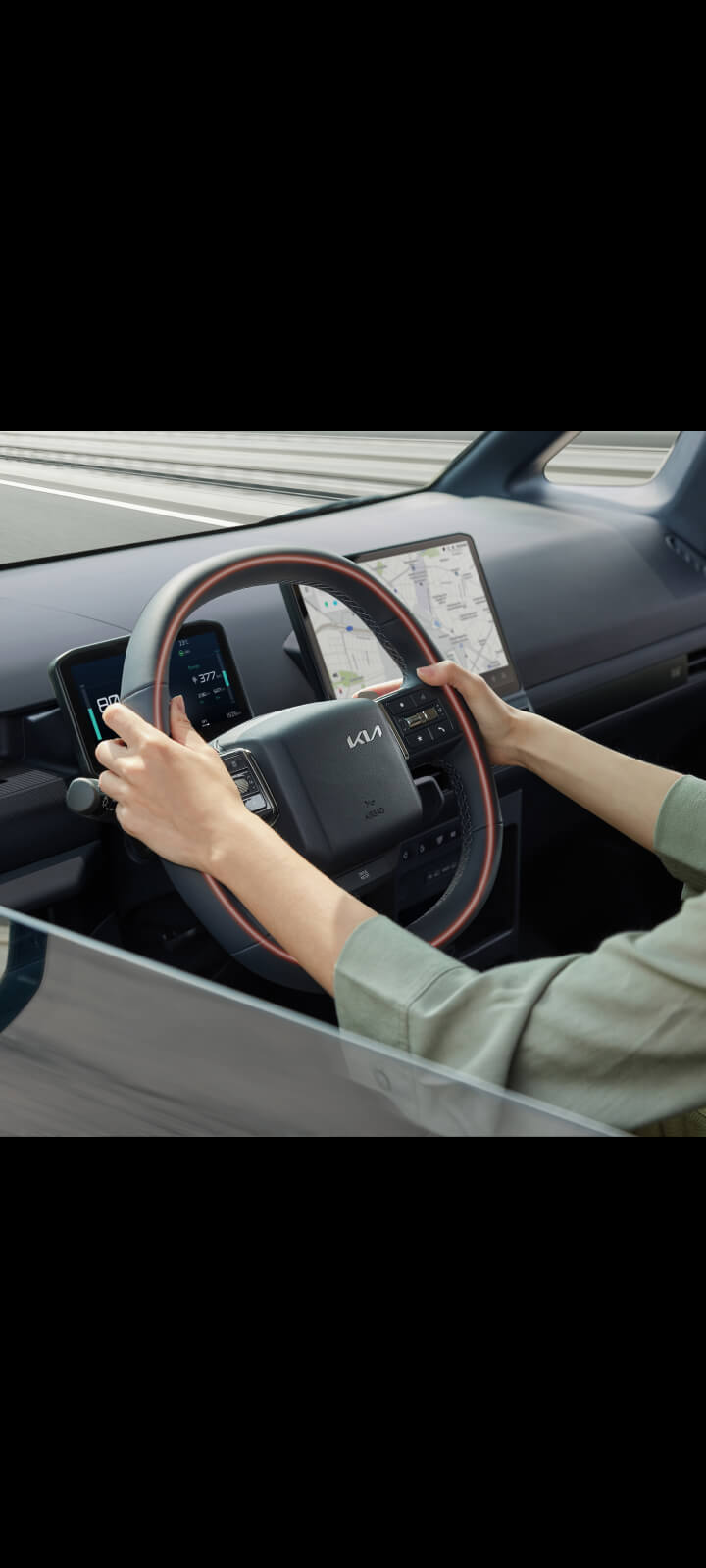 Close-up of the Kia PV5 Passenger steering wheel with driver’s hands