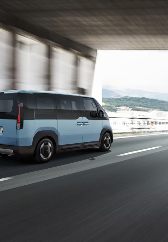 Rear view of the Kia PV5 Passenger driving on highway with another van ahead