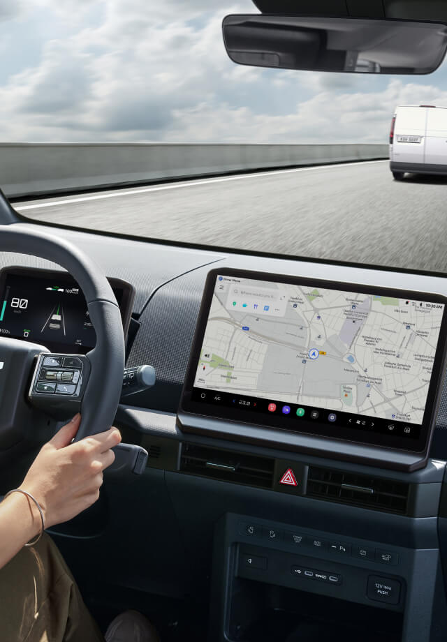 Interior view from driver’s seat with hands on wheel and navigation screen visible