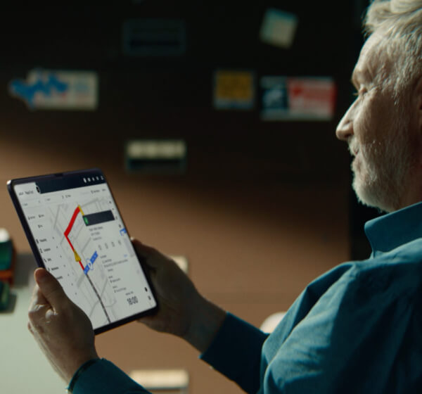 Old man holding a tablet displaying vehicle fleet analytics