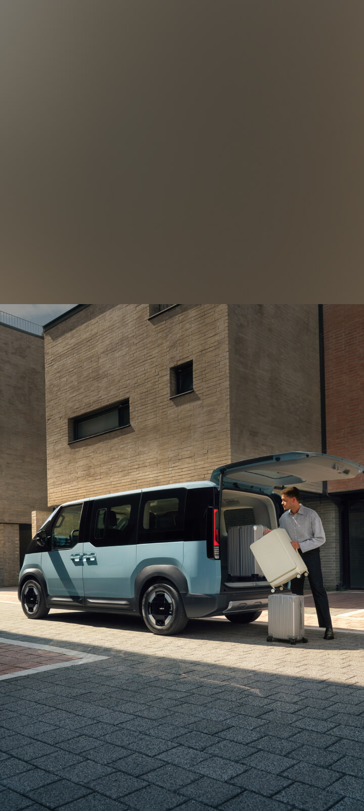 The Kia PV5 Passenger parked outside a laundromat with the rear door open, showing laundry being loaded and unloaded