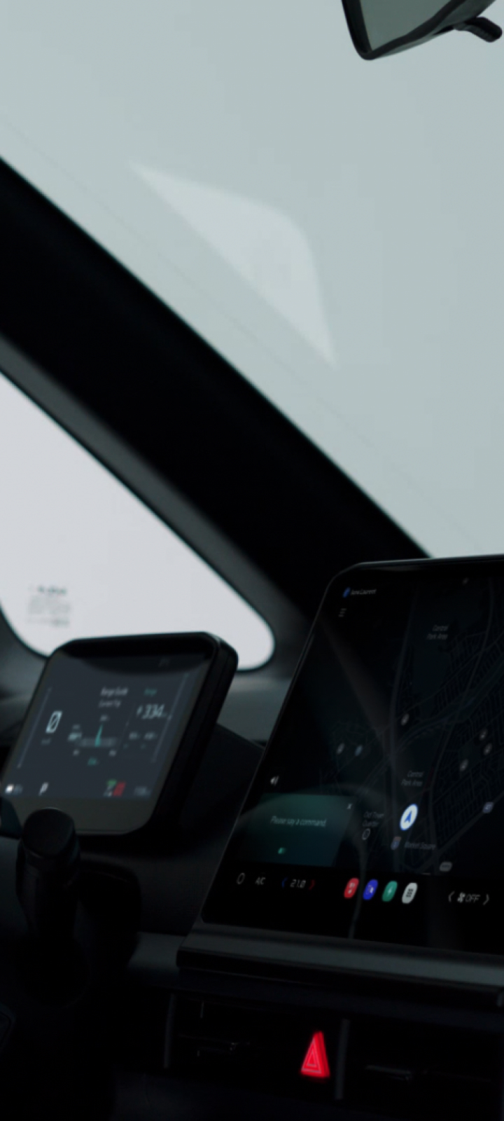 Driver holding the steering wheel with two digital displays visible in the vehicle interior