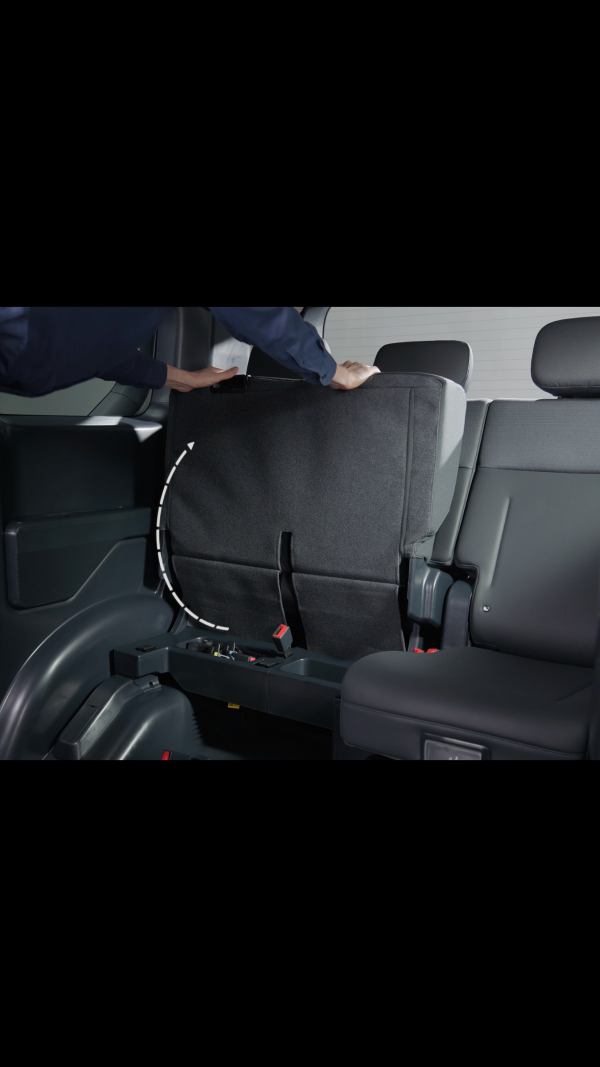 60:40-Klappsitz im Fond des Kia PV5 WAV, hochgeklappt, um Platz für einen Rollstuhl zu schaffen – der danebenliegende Sitz bleibt für eine Begleitperson verfügbar.