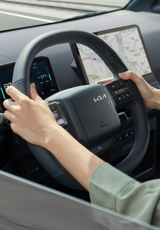 Fahrer hält das Lenkrad des Kia PV5 WAV – die Hands-on-Erkennung überwacht den Kontakt für mehr Fahrsicherheit.