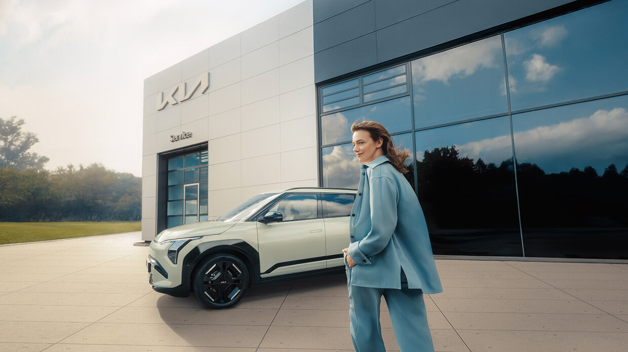 Eine Frau steigt gerade in ihren frisch gewarteten Kia EV3 vor einem Kia-Autohaus ein