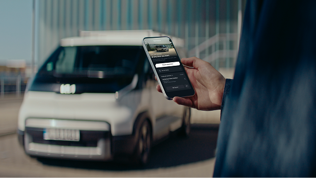 Young architect booking a Fast Lane Service appointment on the Kia App beside his Kia PV5.