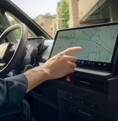 Driver taps on the center screen of his Kia PV5.