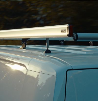 Close-up of Kia Roof Rack Gallery and Roof Rack Roller mounted on a white Kia PV5.