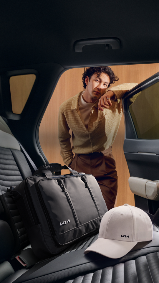Man placing a Kia Laptop Bag and Kia Sports Cap on the rear seats of his Kia EV4.