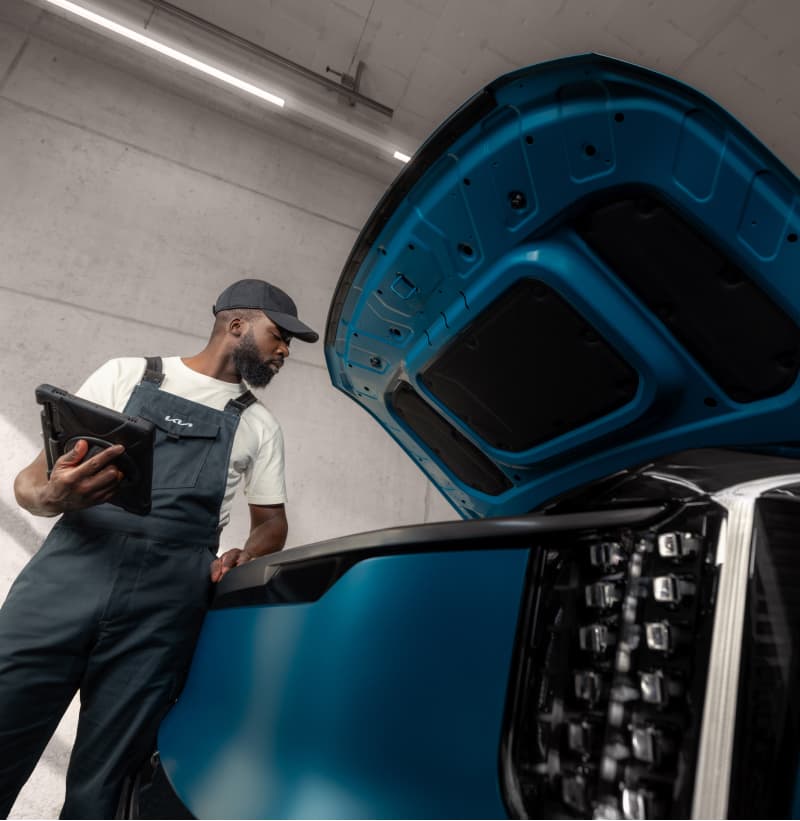 Kia Techniker führt einen Kia EV Fahrzeug-Check mit dem Kia EV Testprotokoll durch.