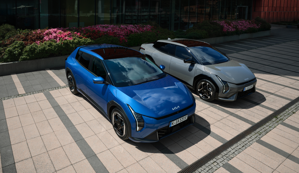 Two Kia EV4 vehicles parked side by side in front of a city building.