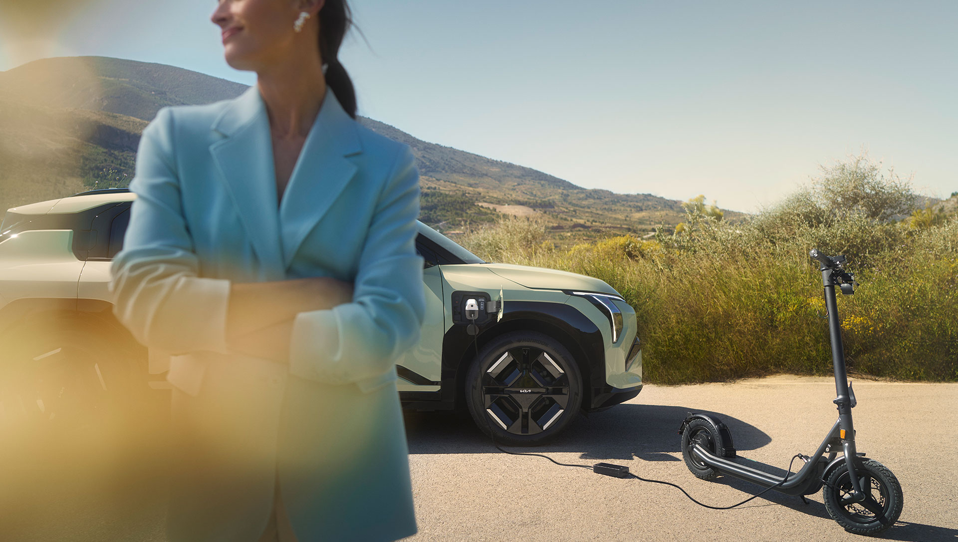 A woman stands next to a scooter and an EV3 vehicle