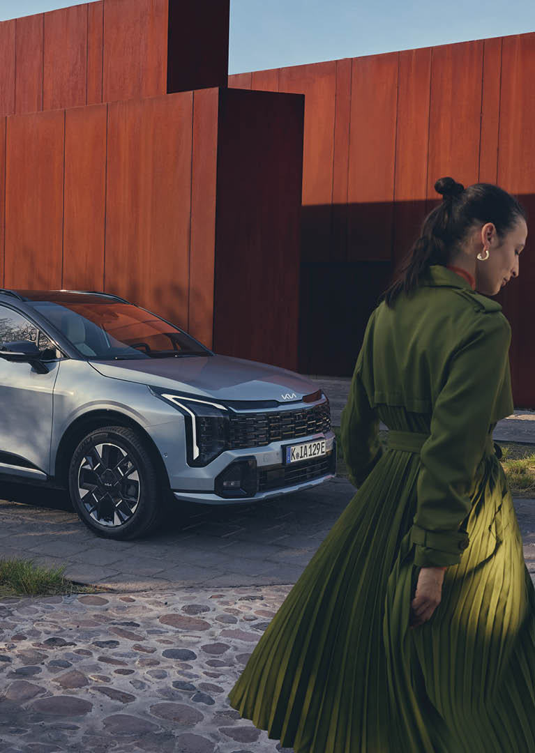 Kia Sportage i sidoprofil med en modell stående bredvid