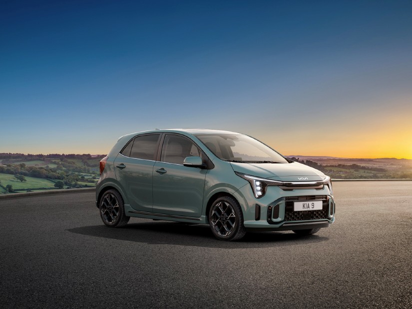 Green Kia Picanto parked on an open road with a scenic countryside backdrop at sunset
