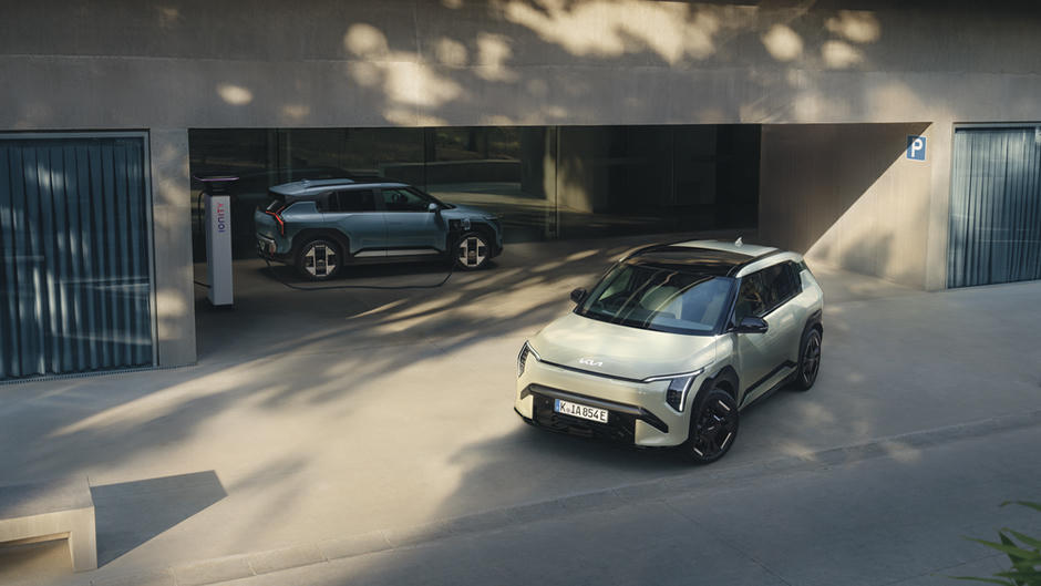 Two Kia EV3’s. EV3 Air in Frost Blue is charging, whilst the EV3 GT-Line S in Pistachio Green is parking.