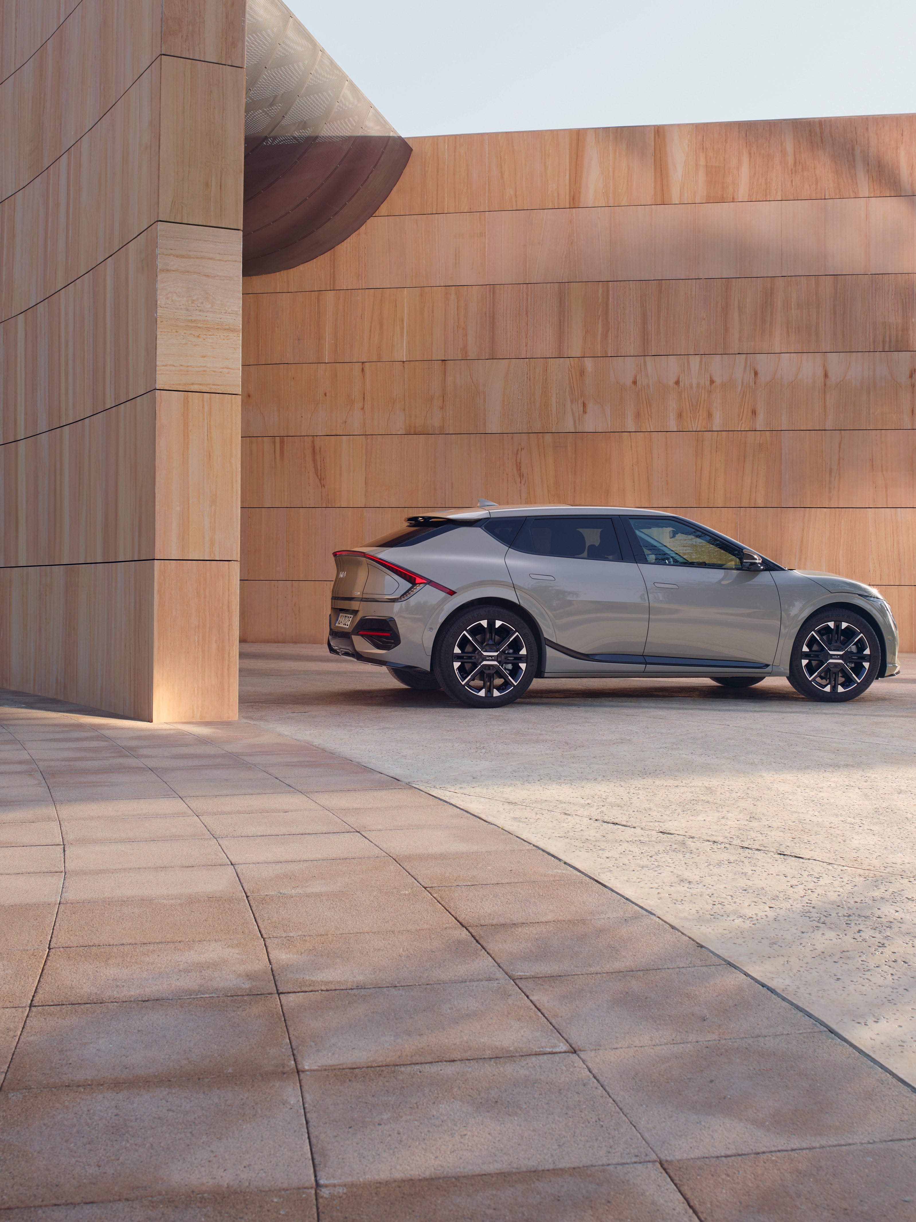 A side angle of the Kia EV6 parked beside a contemporary wood-paneled structure.